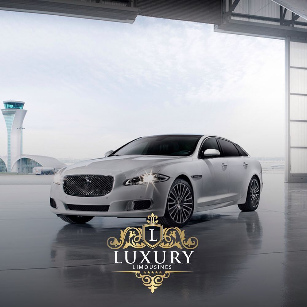 White luxury Jaguar-style sedan parked in airport hangar with control tower Las Vegas