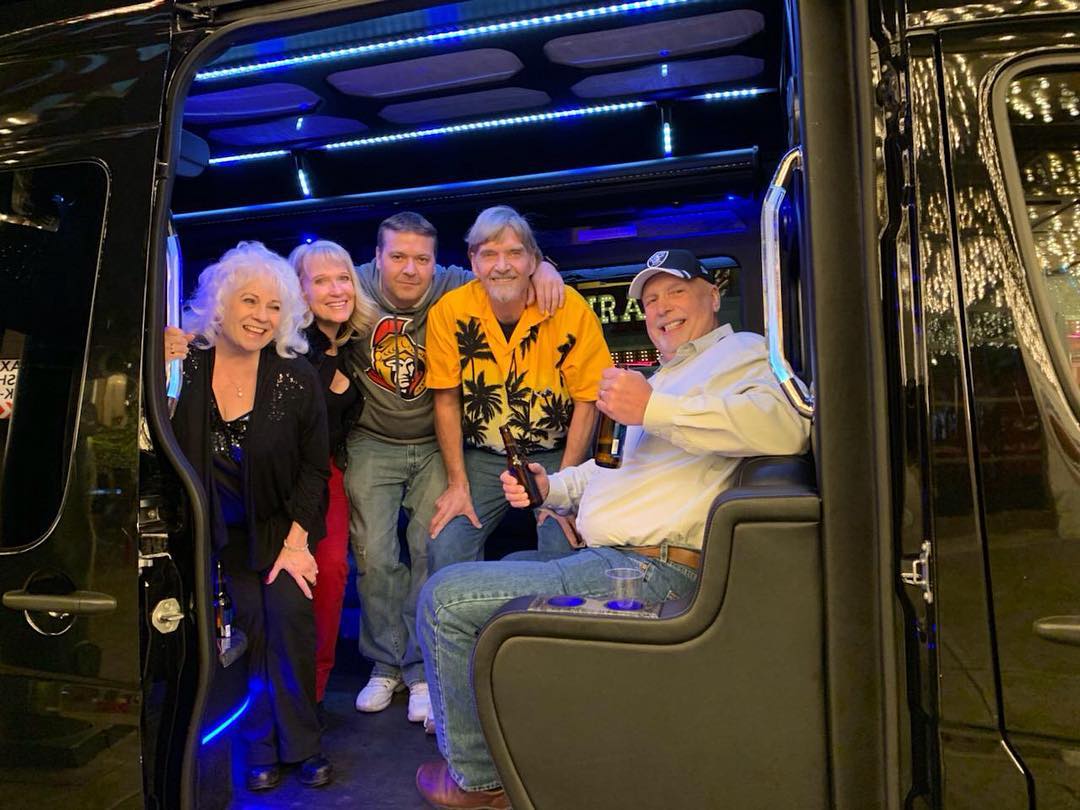 Party bus interior with blue LED lighting and group seated Las Vegas prom school dance transportation