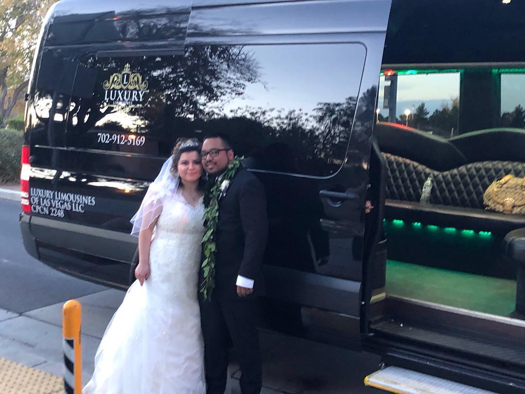 Bride and groom standing together in front of black Mercedes Sprinter with open door Las Vegas wedding