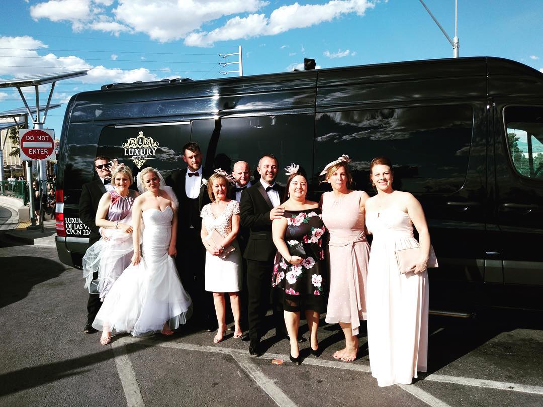 Bride groom and full wedding party posing in front of black Mercedes Sprinter Las Vegas sunny day